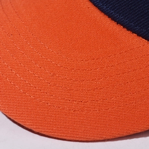 Macro shot of orange baseball cap visor featuring precision stitching and navy blue fabric