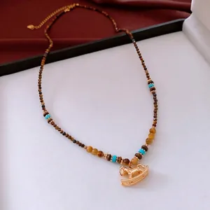 Collier en perles d'œil de tigre avec pendentif cheval doré sur présentoir rouge et blanc