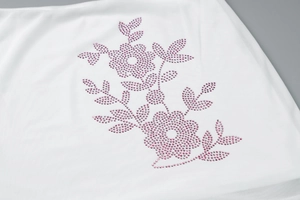 Detailed view of pink rhinestone floral pattern on high-quality white fabric garment