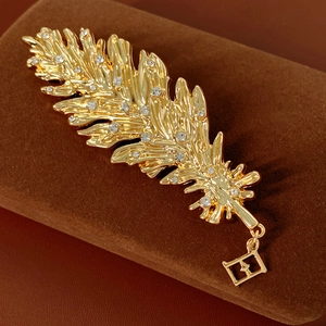 Detail of a golden feather brooch with crystal rhinestones on a brown velvet surface