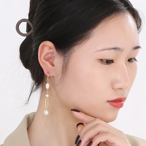 Détail d'une boucle d'oreille rétro à pampille en perle plaqué or 18 carats sur un mannequin
