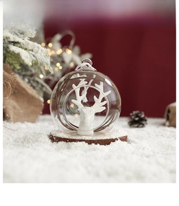 Macro detail of clear glass Christmas ball featuring white reindeer head and wooden base
