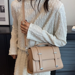 Chic beige PU leather crossbody bag with top handle and adjustable strap worn by a model