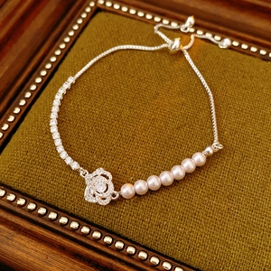 Detail of adjustable flower bracelet with pink pearls and cubic zirconia on green velvet