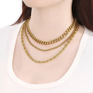 Close-up of layered 18K gold plated Cuban and twist chain necklaces on female model neck