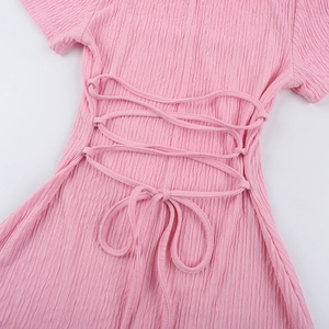 Détail d'une robe rose avec laçage croisé au dos et tissu plissé texturé unique