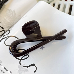 Close-up of deep brown resin hair claw clip on magazine with polished glossy finish