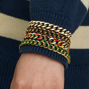 Fashionable golden Cuban chain bracelets with colorful enamel accents on model's wrist