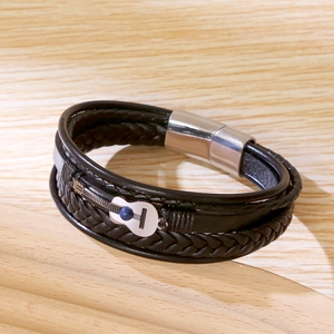 Détail du bracelet en cuir tressé avec breloque guitare et perle bleue sur bois