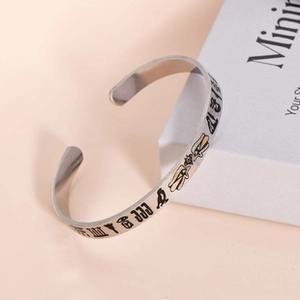 Dettaglio ravvicinato di un bracciale aperto in acciaio al titanio argento con incisioni