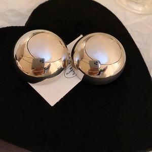 Macro detail of large silver mirror finish spherical stud earrings on black heart base