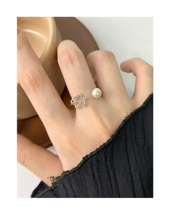 Close-up of S925 sterling silver hollow flower ring with white pearl on woman's finger