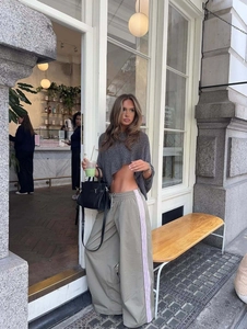 Women's summer grey knit shrug top with green wide-leg pants and black handbag