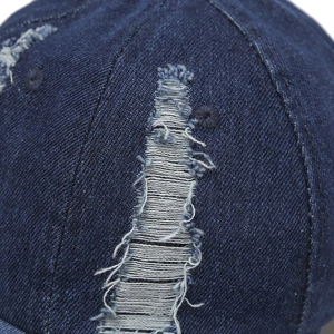 Macro shot of dark blue denim baseball cap featuring distressed rip details and texture