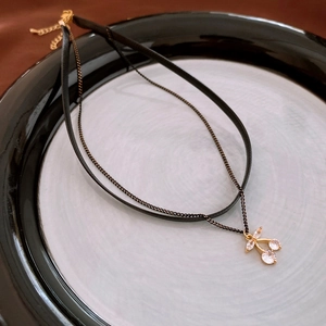 Detail of double-layer cherry choker with black leather cord and sparkling zircon pendant
