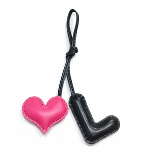 Detail of pink heart and black letter L leather charm with white hand-stitched edges