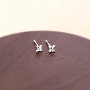 Minimalist square silver stud earrings with clear zircon stone on a wooden surface