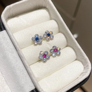 Nahaufnahme glitzernder Blumenohrstecker mit blauem und rosa Zirkon in einer Schmuckschatulle