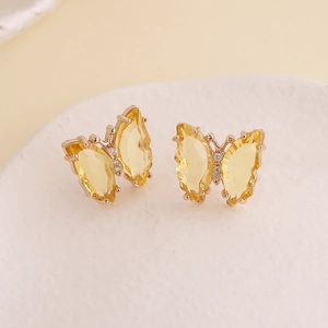 Detailed view of yellow butterfly stud earrings with crystal facets and gold plating