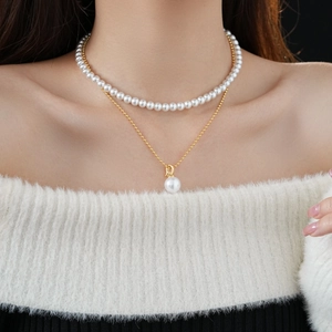 Detail of layered gold-plated necklace with white pearls and D letter pendant on model