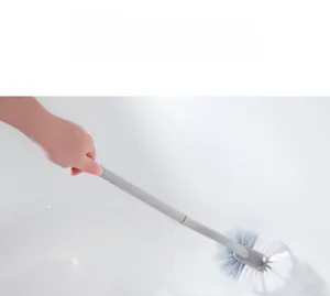 Detail of ergonomic curved long handle toilet brush cleaning white bathroom surfaces