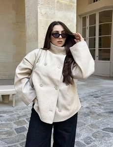 Detail of oat-colored double-breasted short wool coat with stand collar on model
