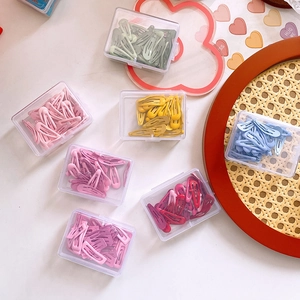 Detailed top view of colorful metal snap hair clips organized in clear rectangle boxes