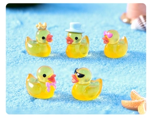 Macro shot of 5 mini resin ducks with accessories on blue beach sand micro landscape