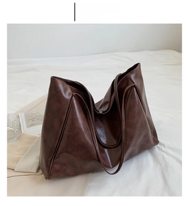 Detail view of coffee brown faux leather tote bag with soft texture and slim shoulder strap