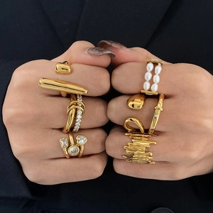 Detailed view of layered gold zircon rings with pearl accents on fingers