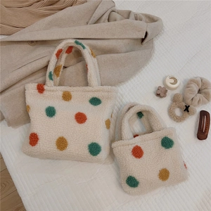 Flat lay of small and large plush polka dot tote bags on soft winter textures