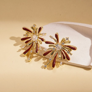 Macro shot of gold firework heart earrings with red enamel and zircon on stone
