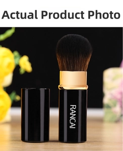 Detail of portable retractable makeup brush with black glossy finish and gold metal ferrule