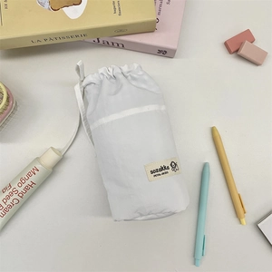 Close-up of a white cotton drawstring pouch with a minimalist dog graphic brand label