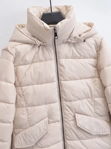 Detail of light beige quilted jacket showing hooded stand collar and premium texture