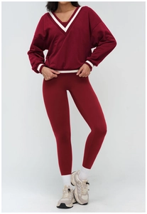 Detail of burgundy V-neck sweatshirt with white stripe trim and high waist yoga pants