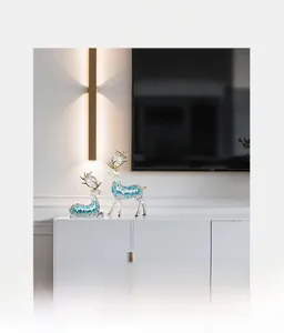 Detail of blue resin elk figurines with gold accents on a modern white TV cabinet