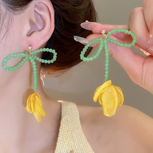 Dettaglio orecchini a fiocco con perline verdi e petali di tulipano in tessuto giallo