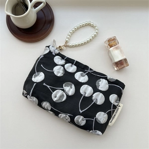 Close-up of cherry jacquard pattern and pearl handle on a sleek black storage pouch