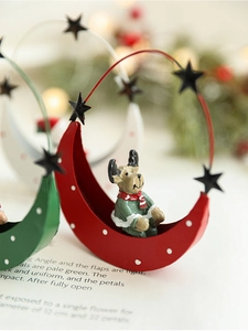 Close-up of a Christmas moon ornament featuring a reindeer figurine on a metal base