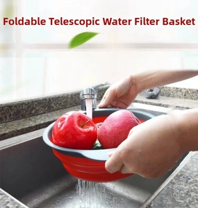 Red and grey foldable silicone colander used for washing fresh apples in a kitchen sink