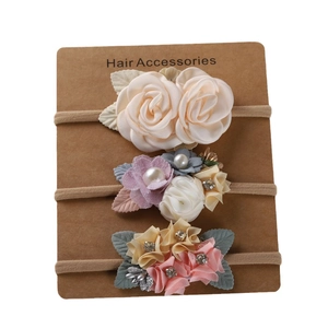 Détail de trois bandeaux pour bébé en nylon avec fleurs en tissu faites à la main