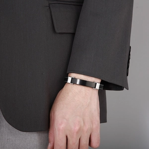 Men's minimalist black leather and titanium steel bracelet worn with professional business attire