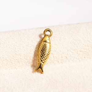 Macro shot of a gold fish pendant with scale texture and top loop on beige fabric