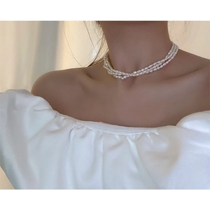 Detailed view of elegant triple-layered freshwater baroque pearl necklace on a model