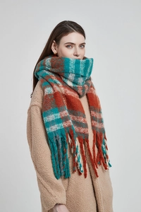 Close-up of thick checkered scarf with tassels in orange and teal plaid wool