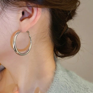 Close-up of a silver metal C-shaped hoop earring worn by a model in a minimalist style