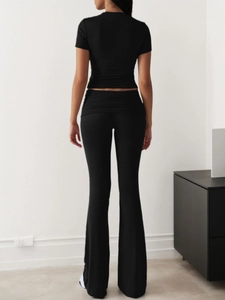 Rear view of women's black slim-fit short sleeve top and flare trousers lounge set