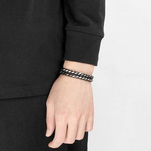 Gros plan d'une gourmette en acier inoxydable noir mat portée par un mannequin masculin