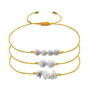Detail of three yellow woven bracelets with white natural stones and gold beads